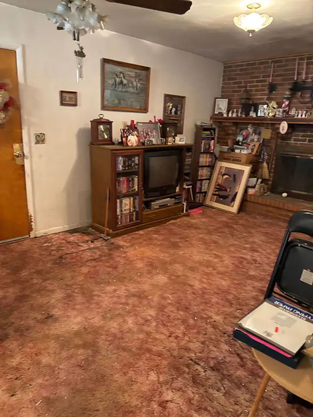 Same living room with the floor and bulk clutter cleared, family furnishings still in place, partway through the estate cleanout