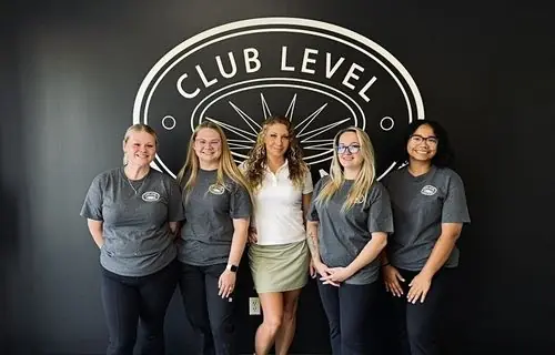 Five Club Level Cleaning staff in company polos in front of the Club Level wall logo